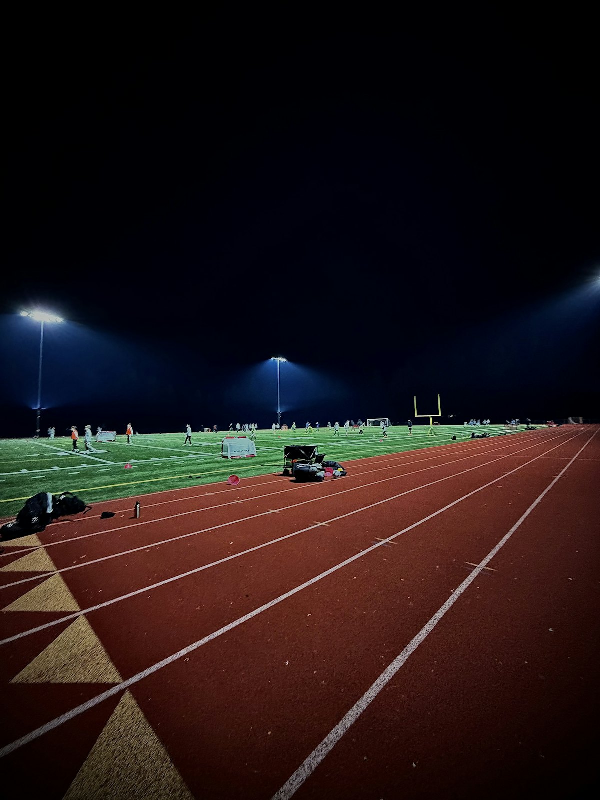 An empty running track under stadium lights at night